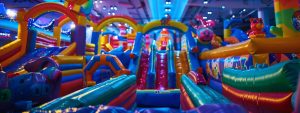 a vibrant indoor party scene featuring an array of colorful inflatable attractions and cheerful decorations, capturing the lively atmosphere of a children's event filled with joy and excitement.